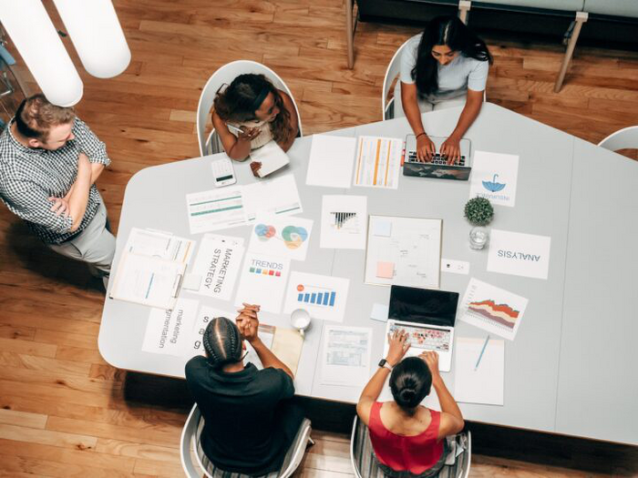 A team of people working on a project planning phase with papers all over the table